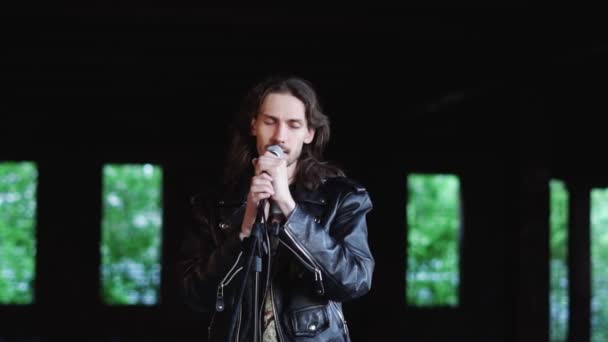 Um cantor canta em um microfone em um prédio antigo — Vídeo de Stock