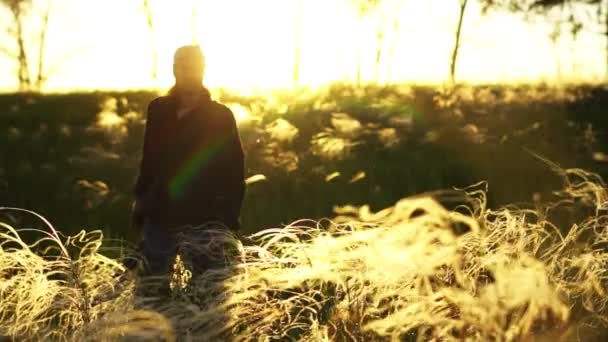 Un homme marche sur un champ au coucher du soleil — Video