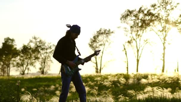 Парень играет на гитаре на поле — стоковое видео