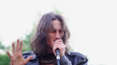 Şarkıcı mikrofonda sokakta şarkı söylüyor.