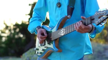 Adam sahada gitar çalıyor.