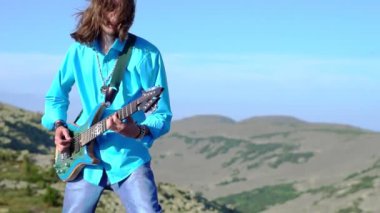 Adam sahada gitar çalıyor.