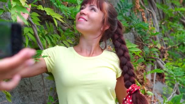 Une fille pose pour une photo sur le fond des arbres — Video