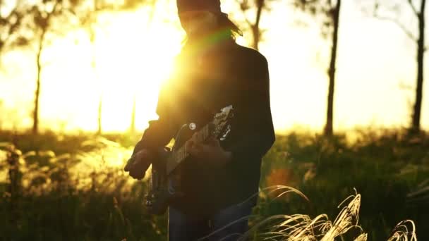 Een muzikant speelt gitaar bij zonsondergang — Stockvideo