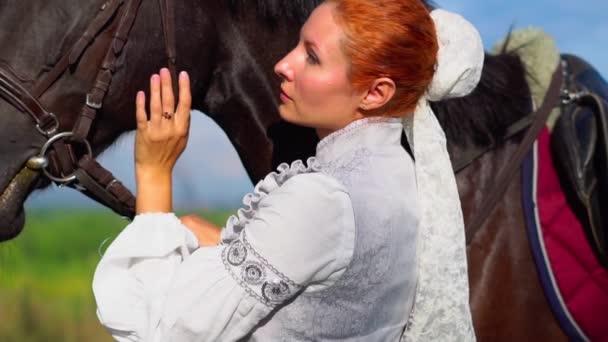En pige i en gammel kjole ved siden af en hest – Stock-video