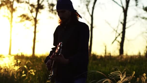 Een muzikant speelt gitaar bij zonsondergang — Stockvideo