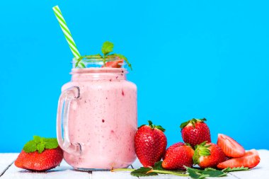 Meyve smoothie çilek, milkshake taze çilek ile mavi arka plan üzerinde kavanoza karışık