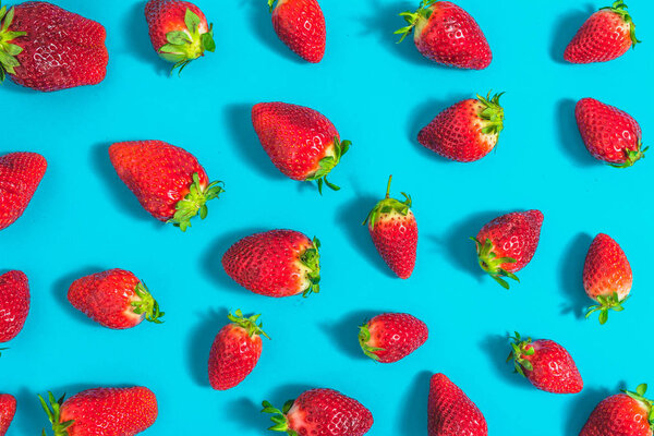 Red pattern of strawberries on blue background, fresh strawberry, flat lay, overhead