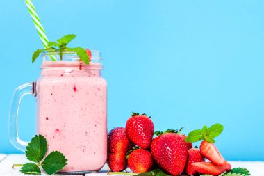 Meyve yüzlü ile sağlıklı tatlı çilek, taze çilek veya berry meyve yoğurt kavanoz mavi zemin üzerine muzlu süt