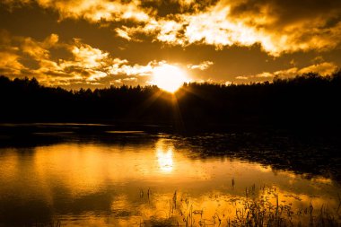 Göl manzara sonbahar, günbatımı gökyüzü ve güneş ışınları orman, vahşi doğa silüeti üzerinde