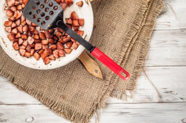 Kızarmış sosis tava ahşap arka plan üzerinde bir küp içinde dilimlenmiş.