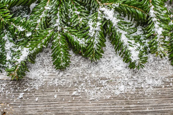 モミの木の枝と木の上の雪でクリスマス木製の背景 — ストック写真