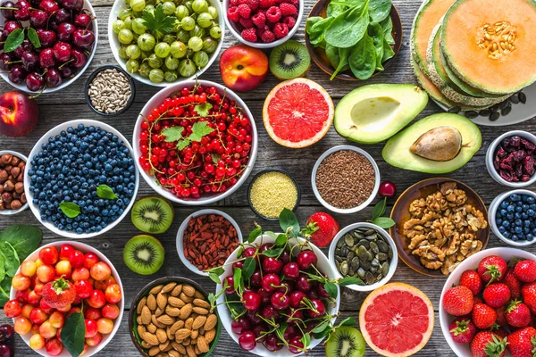 Sağlıklı yemek masada. Odaya bir kase ile çeşitli superfood, Vejetaryen diyet meyve, fındık ve çilek ile.