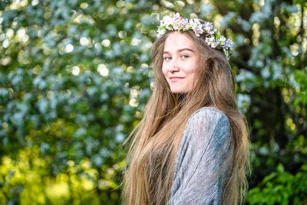 美しい若い女性庭で春を楽しんでいます 髪に花を持つ少女 — ストック写真