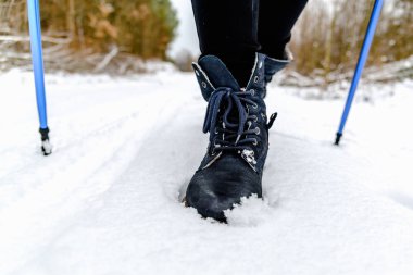 Karda yürüme aktif kadınlarda. Bot ve bacaklar detay. Açık havada kış spor Nordik yürüyüş veya yürüyüş ile kar üzerinde sopa.
