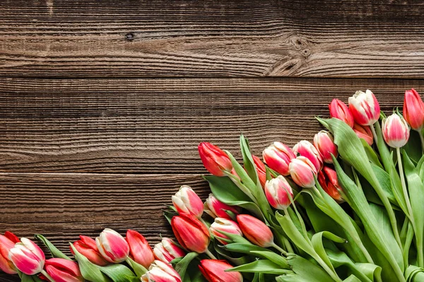 Flores frescas sobre mesa de madera. Ramo de tulipanes de primavera, vista superior. Antecedentes para el día de la mujer o el concepto de tarjeta del día de la madre . — Foto de Stock