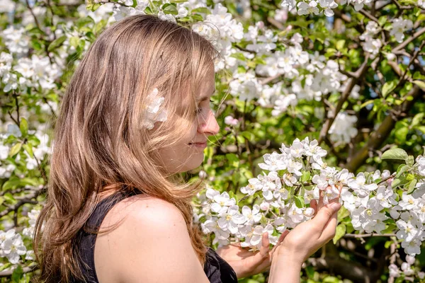 Hermosa mujer entre los manzanos en flor en el jardín de primavera — Foto de Stock