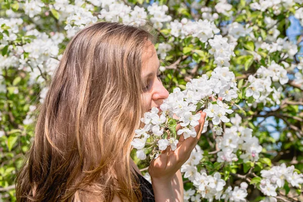 Piękna kobieta wśród wiosennych kwitnących drzew pachnące kwitnącą gałąź jabłko — Zdjęcie stockowe