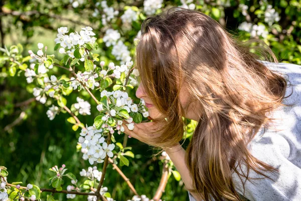 Piękna kobieta pachnąca kwitnących kwiatów jabłoni w wiosennym ogrodzie — Zdjęcie stockowe