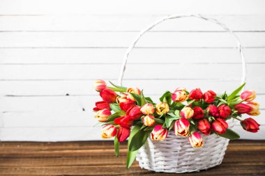 Ahşap masada bir sepet içinde bir demet lale. Anneler günü çiçekler.