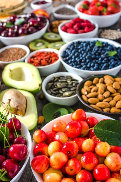 Ciliegie fresche e altri cibi sani in tavola. Colazione in ciotola con super cibi, frutta biologica, noci e frutti di bosco . — Foto Stock