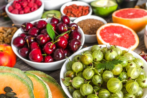 Buah beri segar dan makanan sehat lainnya di atas meja. Sarapan yang berisi makanan super, nutrisi vegetarian organik seperti buah-buahan, kacang-kacangan dan biji-bijian . — Stok Foto