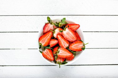 Taze olgun çilek. Dilimlenmiş çilek, taze meyve salatası, üst görünüm ile kase