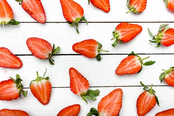 Fresh strawberries pattern. Texture of strawberry slices on white wooden background, food flat lay.