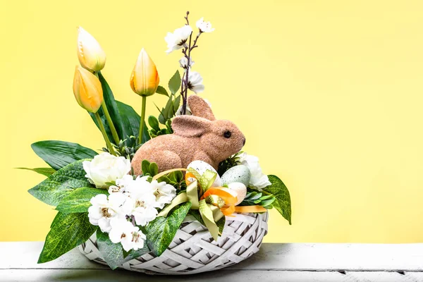 Sfondo pasquale con decorazione, coniglio pasquale e fiori primaverili in un cesto — Foto Stock
