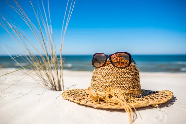 Sombrero y gafas de sol. Accesorios de playa para protección solar en arena blanca, cielo azul y fondo marino, playa de vacaciones de verano, Báltico, Polonia —  Fotos de Stock