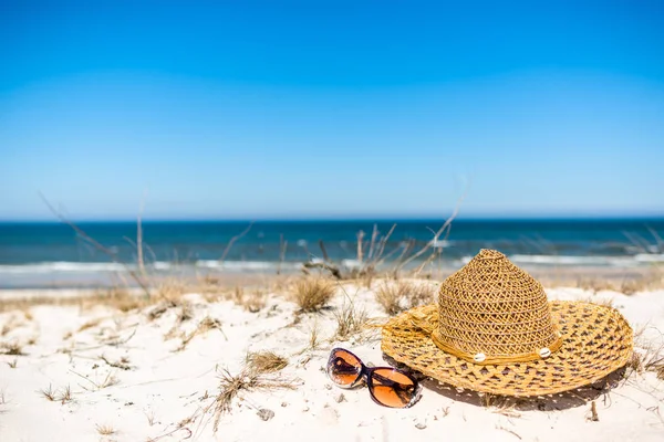 Sombrero de sol y gafas de sol sobre arena. Accesorios de playa de verano - paisaje de vacaciones, Mar Báltico, Polonia . —  Fotos de Stock
