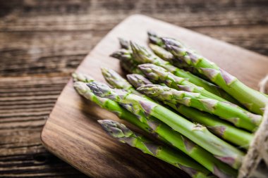 Ahşap tahta üzerinde yeşil kuşkonmaz demet, çiftlik taze sebze pişirme için hazırlanan