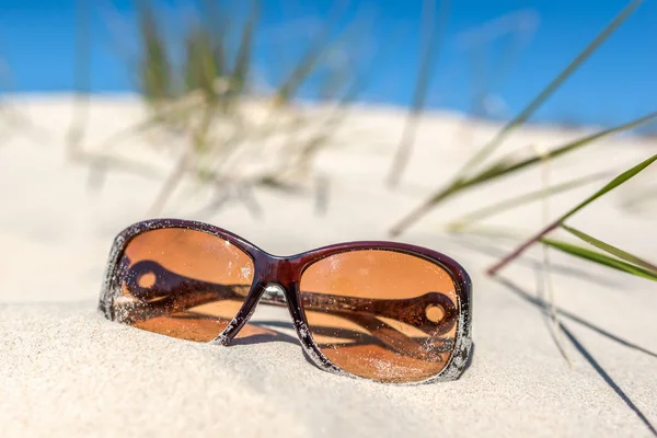 Fondos de verano con accesorios de vacaciones en la playa, gafas de sol en la duna de arena y cielo azul. Concepto de recreación navideña. —  Fotos de Stock