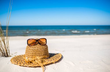 Şapka ve güneş gözlüğü. Beyaz kum, mavi gökyüzü ve deniz arka plan, yaz tatili plaj, Baltık, Polonya güneş koruma için plaj aksesuarları