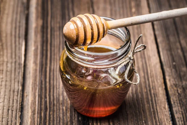 Verre pot de miel et cintre sur fond de bois — Photo
