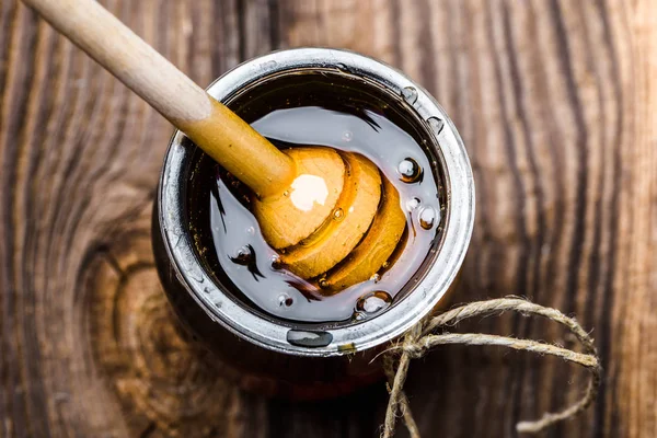 Verre pot de miel et cintre en bois dans le miel, vue du haut — Photo