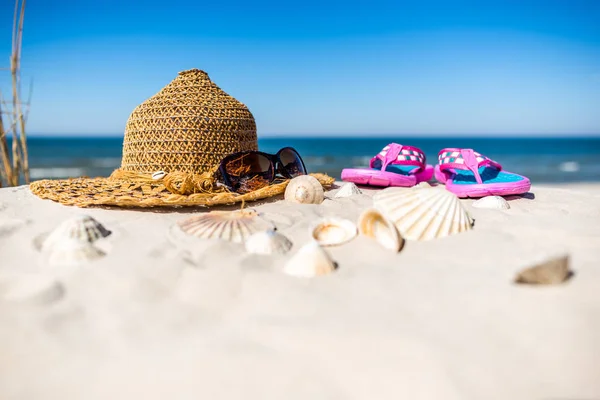 Fondo con accesorios de playa de verano sobre el mar Báltico con arena blanca y cielo azul. Gafas, gorro de sol y chanclas . —  Fotos de Stock