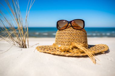 Yaz plaj aksesuarları - kum ve deniz üzerinde güneş şapkası ve güneş gözlüğü. Yaz tatili geçmişi, Baltık Denizi, Polonya.