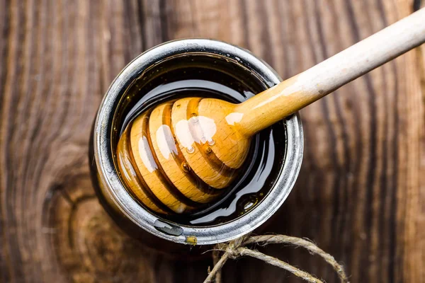 木製の背景に蜂蜜に浸した蜂蜜とディッパーのガラス瓶 — ストック写真