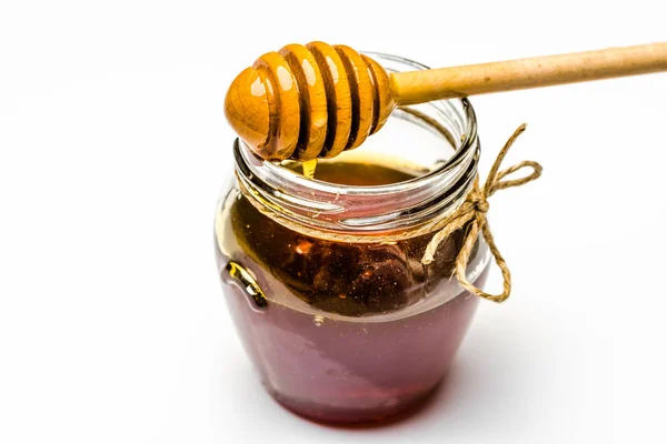 白い背景に暗い蜂蜜の蜂蜜とディッパーのガラス瓶 — ストック写真
