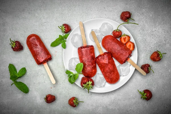 Fruit popsicles, strawberry sorbet with frozen strawberries