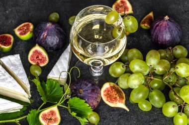 Taze şarap ve peynir tatma. Bir bardak beyaz şarap ve yemek, Fransız peyniri, incir ve üzüm..