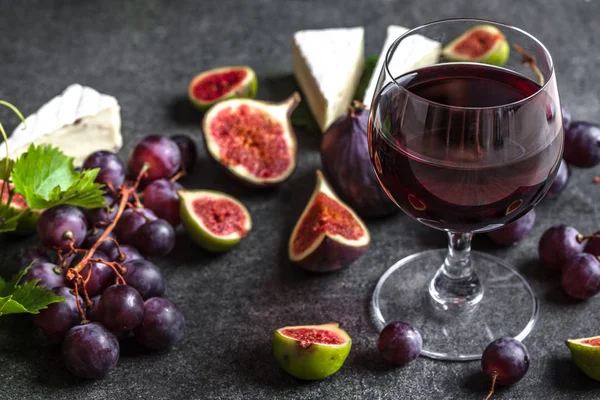 Copo de vinho tinto e aperitivos. Queijo francês, figos e uvas. Degustação de vinho e queijo . — Fotografia de Stock