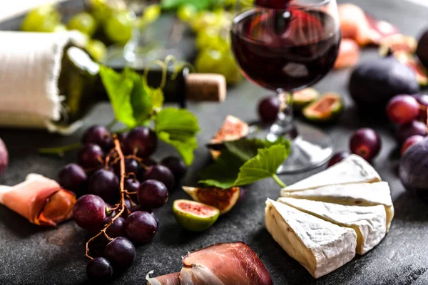 Buffet with wine snack set or french appetizer. Glass and bottle of red wine, cheese, meat and fruit. — Stock Photo, Image