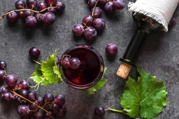 Vinho tinto e uvas. Copo de vinho e garrafa no fundo preto, vista superior, flat lay — Fotografia de Stock
