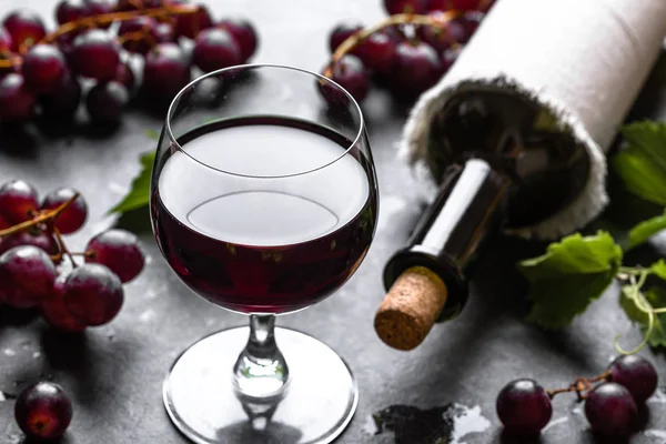 Copo de vinho com uvas vermelhas e garrafa de vinho em uma adega — Fotografia de Stock