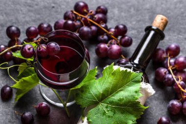 Kırmızı şarap ve üzüm. Siyah arka planda bir bardak şarap ve şişe.