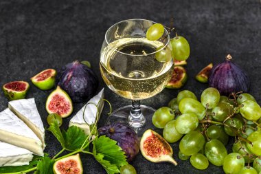 Bir bardak beyaz şarap ve yemek: Fransız peyniri, incir, üzüm.