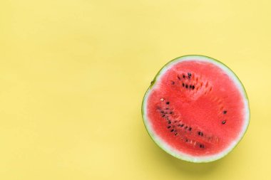 Taze karpuz dilimi, sarı arka planda üst manzara.