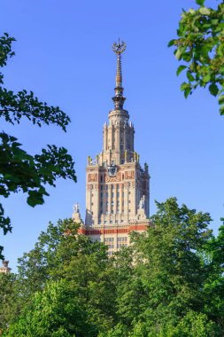 Moskova Devlet Üniversitesi (MSÜ) mavi gökyüzü ve güneşli yaz akşam yeşil ağaçların karşı